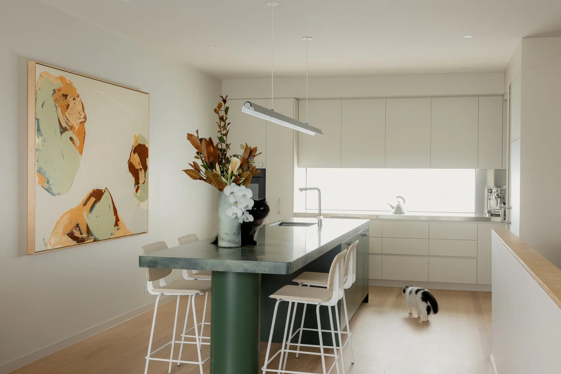 Modern minimalist kitchen interior design featuring a green marble island bench and bespoke cabinetry