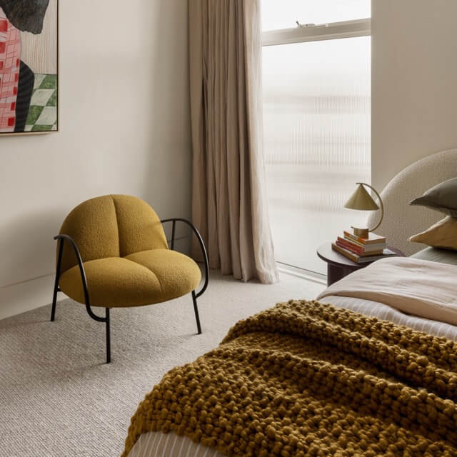 Stylish bedroom with a bright yellow accent chair, part of a Furnishd interior design project.